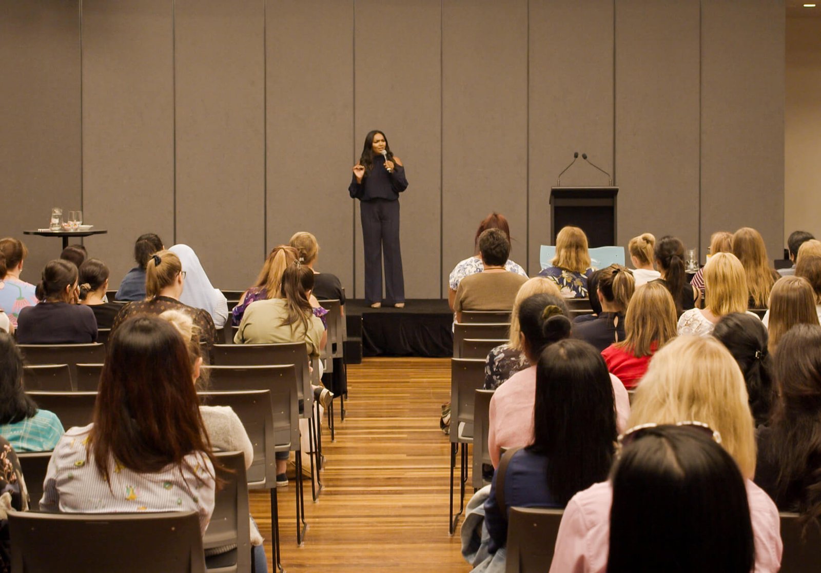 Norliza on stage — full room of corporate attendees