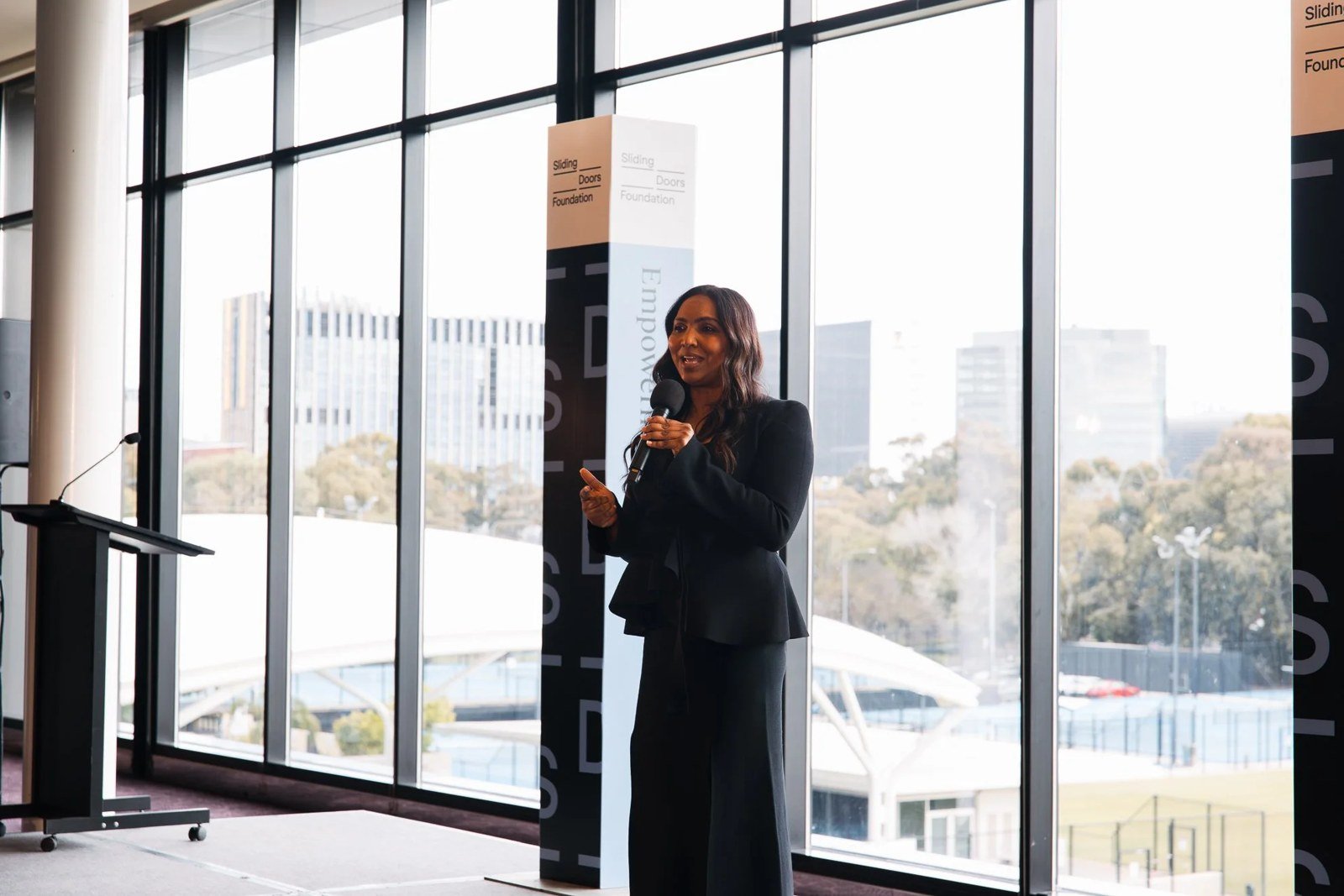Norliza Pavlakos speaking on stage at the Sliding Doors Foundation